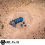 Top-down view of an ARB Esperance 2.0 Rooftop Tent Hard Shell on a blue off-road vehicle, set up in a desert campsite with chairs and table.
