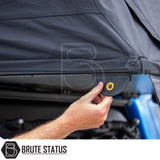 Hand pulling black canvas tab with brass grommet on ARB Esperance 2.0 Rooftop Tent Hard Shell, showcasing vehicle-mounted accessory by Brute Status.