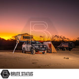 ARB Flinders Rooftop Tent on a pickup, featuring a yellow fabric canopy and ladder, set up at a sunset campsite.