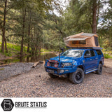Blue 4x4 with ARB Flinders Rooftop Tent deployed, parked on rocky riverbank. Tent enhances comfort and utility for adventurous camping.