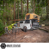 Off-road pickup with ARB Flinders Rooftop Tent, awning, and camping setup in forest clearing, showcasing a compact and comfortable overlanding solution.