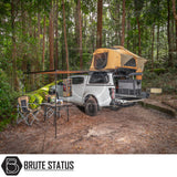Overland camping setup featuring ARB Flinders Rooftop Tent on a white pickup truck with awning, camp chairs, and table, highlighting outdoor adventure and comfort.
