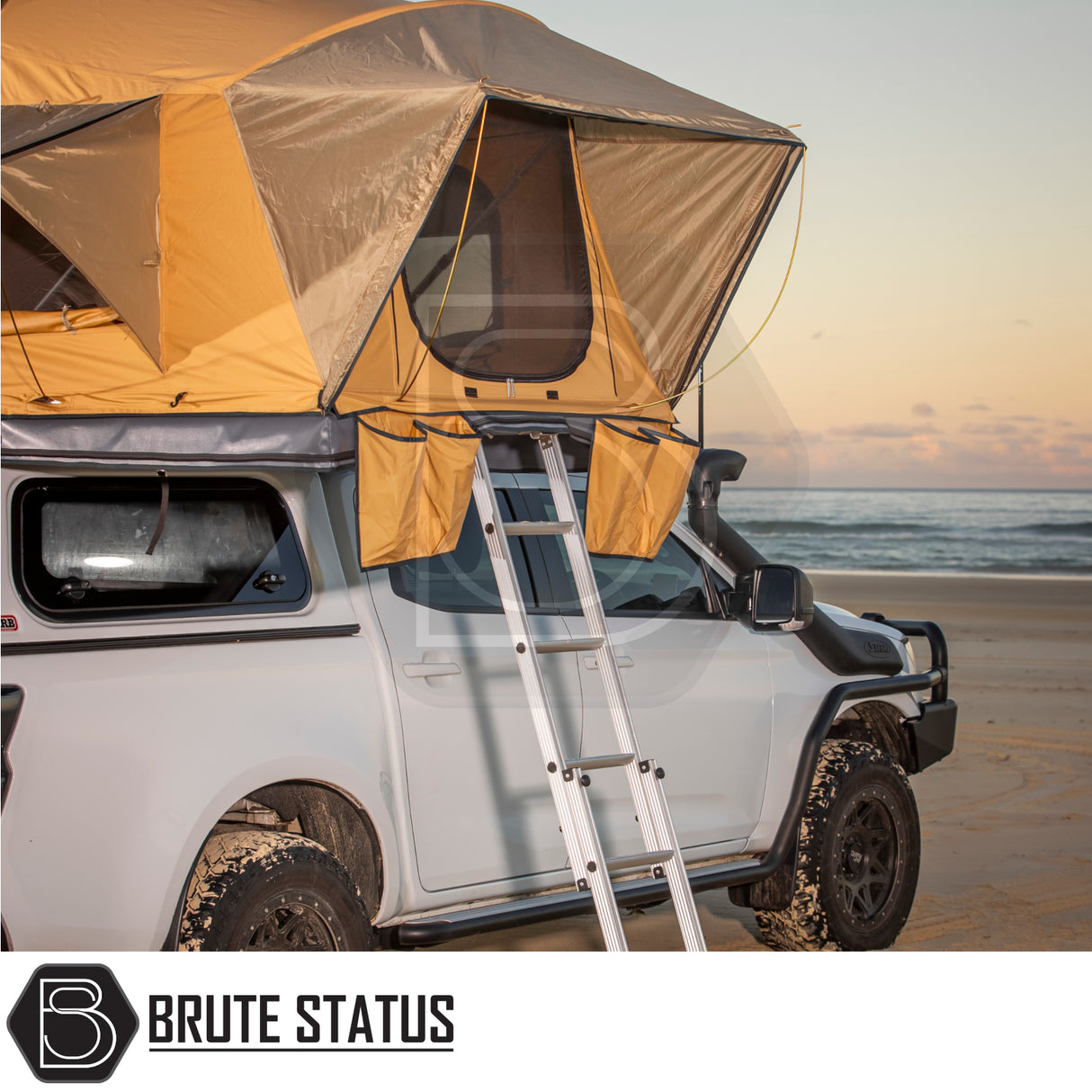 4x4 pickup with ARB Flinders Rooftop Tent on a beach at sunset, featuring a pop-up tan tent and ladder, ideal for adventurous truck enhancements.