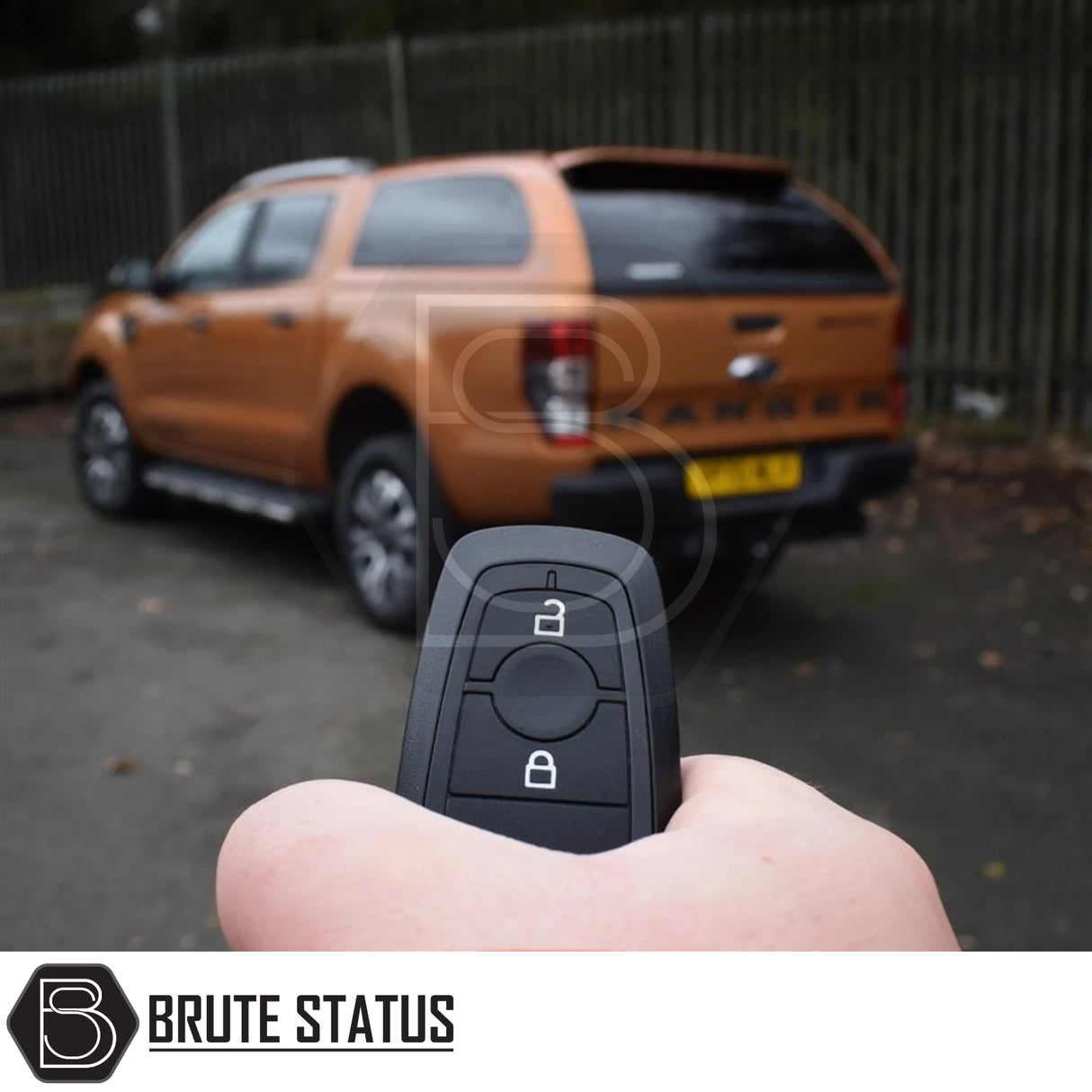 Hand holding key-fob for Ford Ranger 2012-2022 Truckman Grand Hardtop Canopy, showcasing remote locking feature with blurred orange Ford Ranger in background.