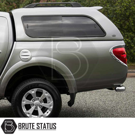 Silver Mitsubishi L200 2010-2015 with Truckman GLS hardtop canopy, showcasing tinted sliding windows, rear taillight, and Brute Status logo watermark.