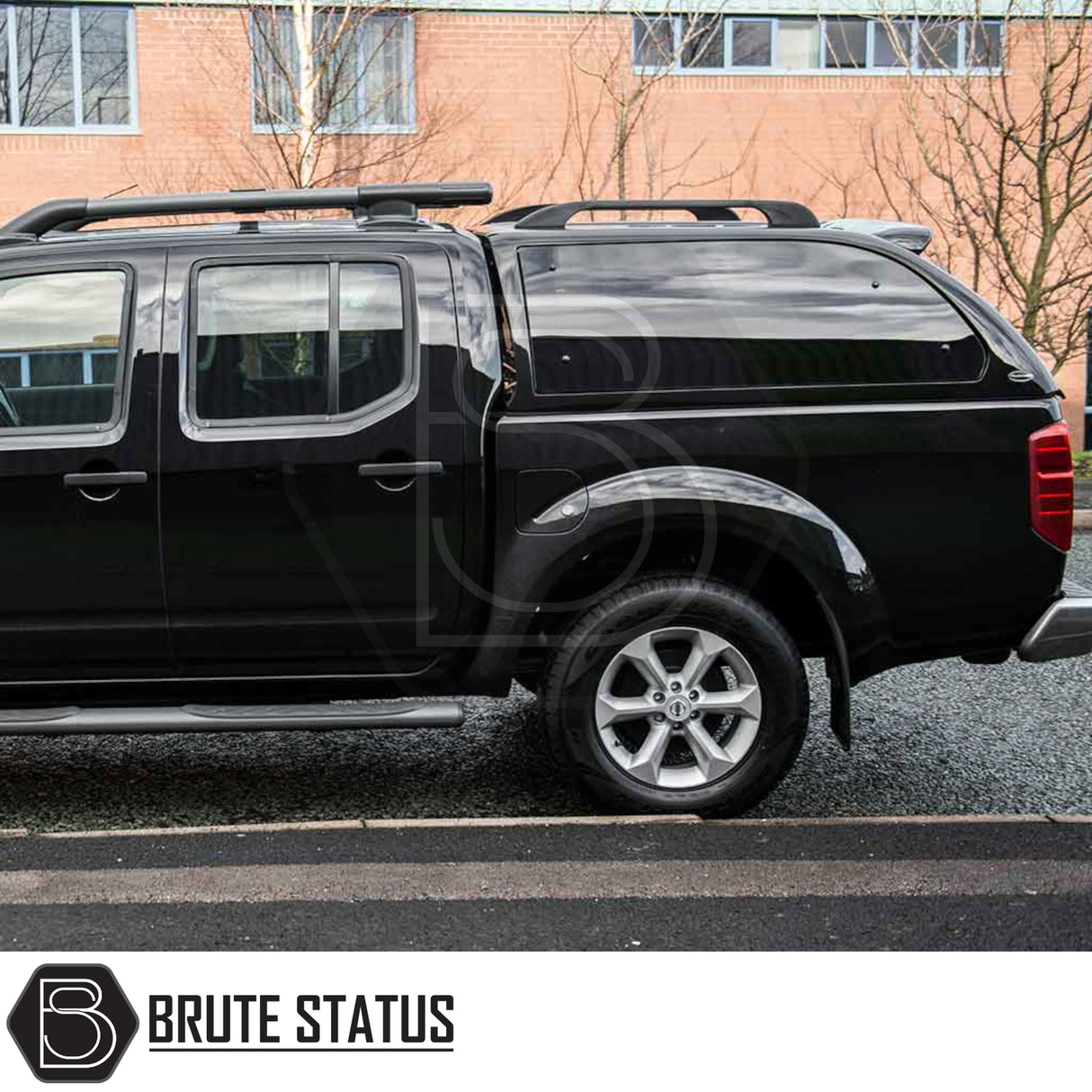 Side view of a black Nissan Navara with a Truckman Grand hardtop canopy featuring tinted windows and roof rails.
