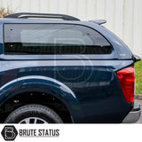 Nissan Navara 2005-2015 D40 Truckman Grand Hardtop Canopy with tinted windows and roof rails, showcasing rear-side profile and “Brute Status” logo.