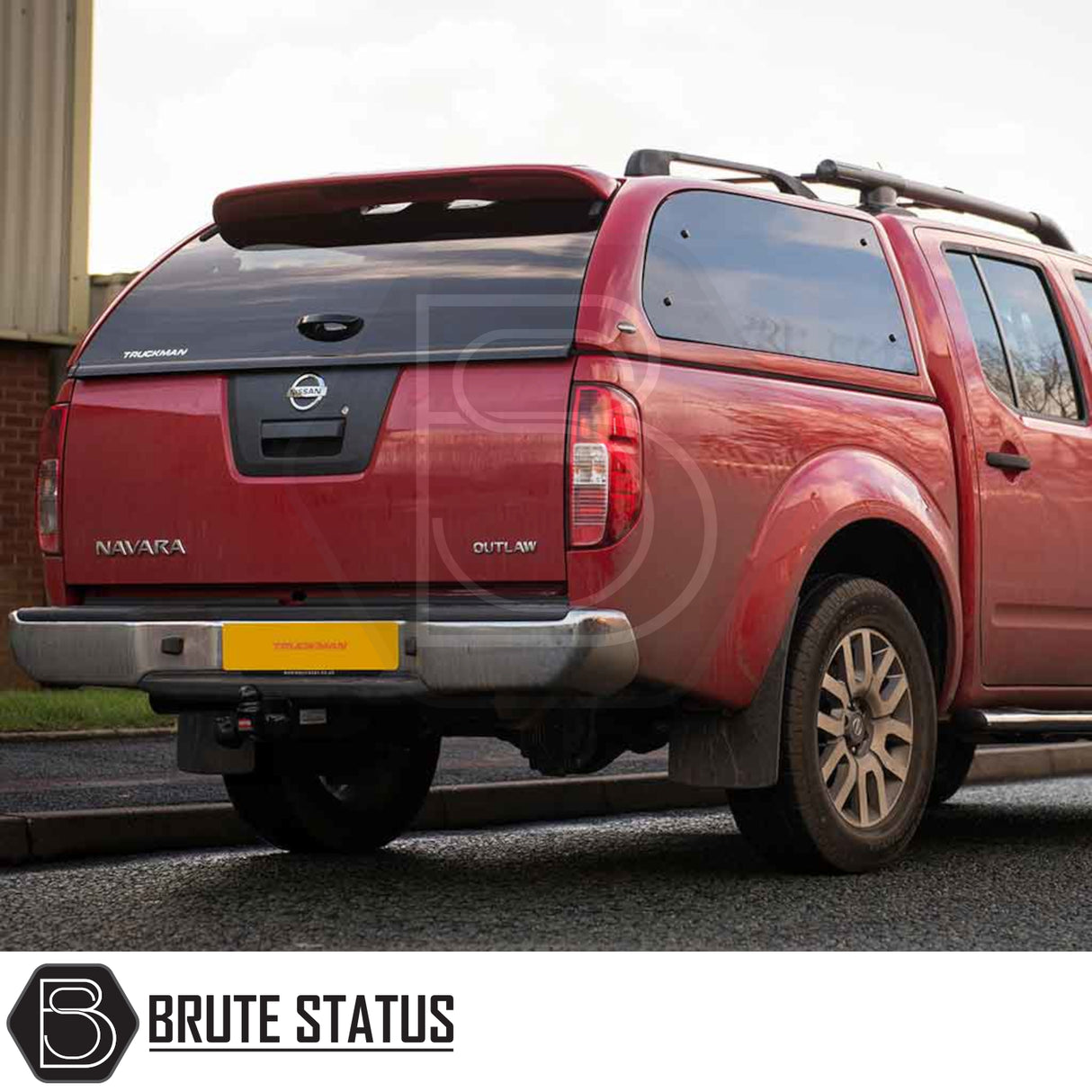 Rear view of a red Nissan Navara with a Truckman Grand Hardtop Canopy, featuring tinted windows and roof racks, highlighting its premium pickup truck accessory.