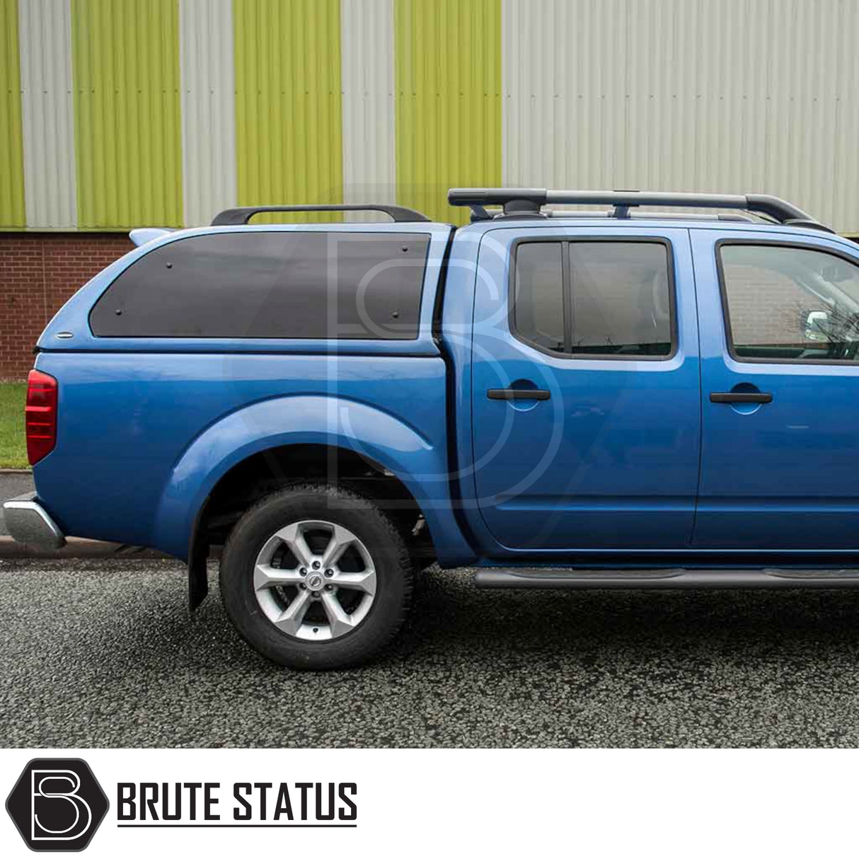 Side view of a blue Nissan Navara 2005-2015 D40 Truckman Grand Hardtop Canopy with remote locking, showcasing tinted windows and roof-rack rails.