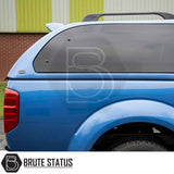 Rear view of a blue Nissan Navara 2005-2015 D40 with a Truckman Grand Hardtop Canopy featuring tinted windows and roof rails, branded by Brute Status.