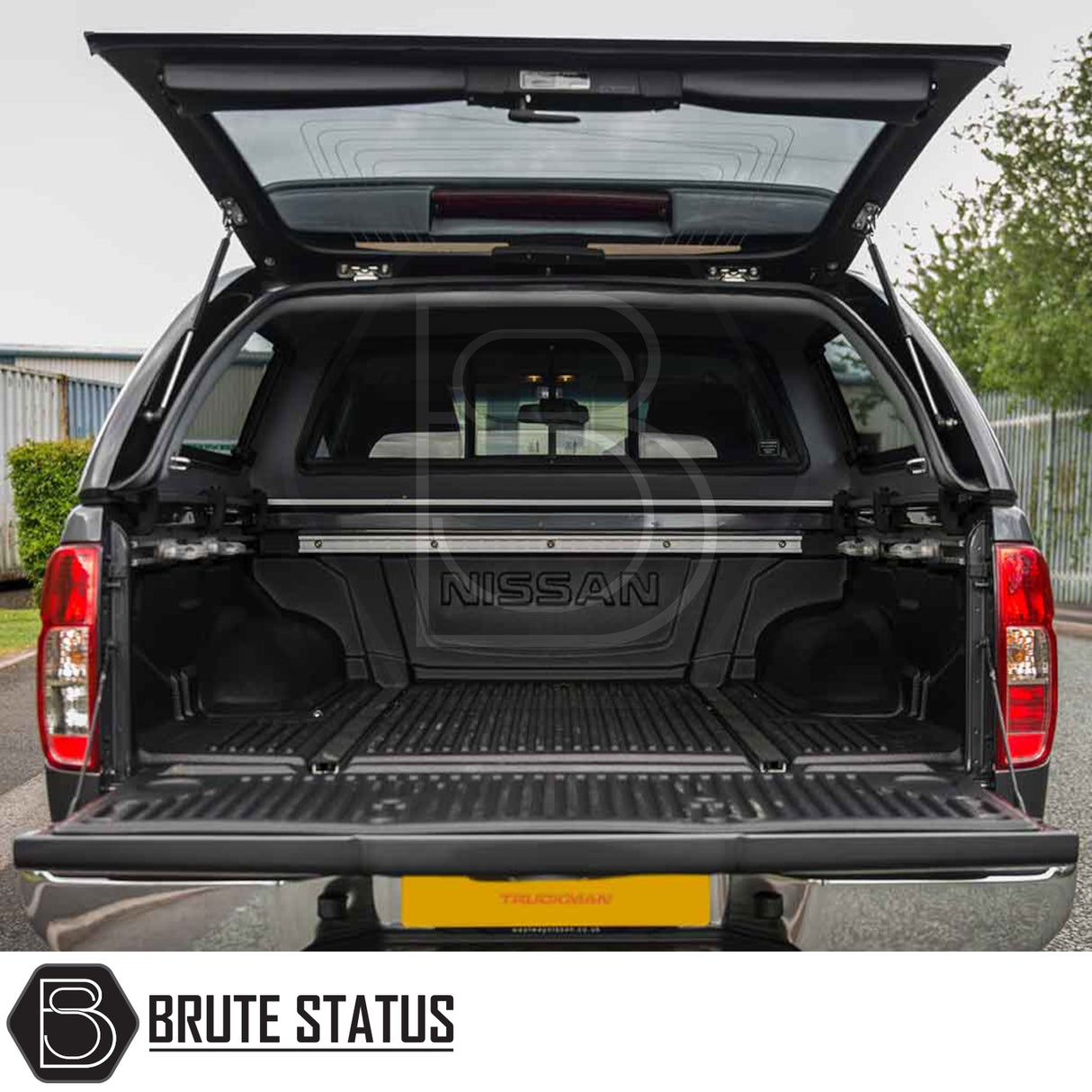 Nissan Navara 2005-2015 D40 Truckman Grand Hardtop Canopy, rear view, reveals empty bed with molded bed-liner and open hardtop, showcasing premium features.