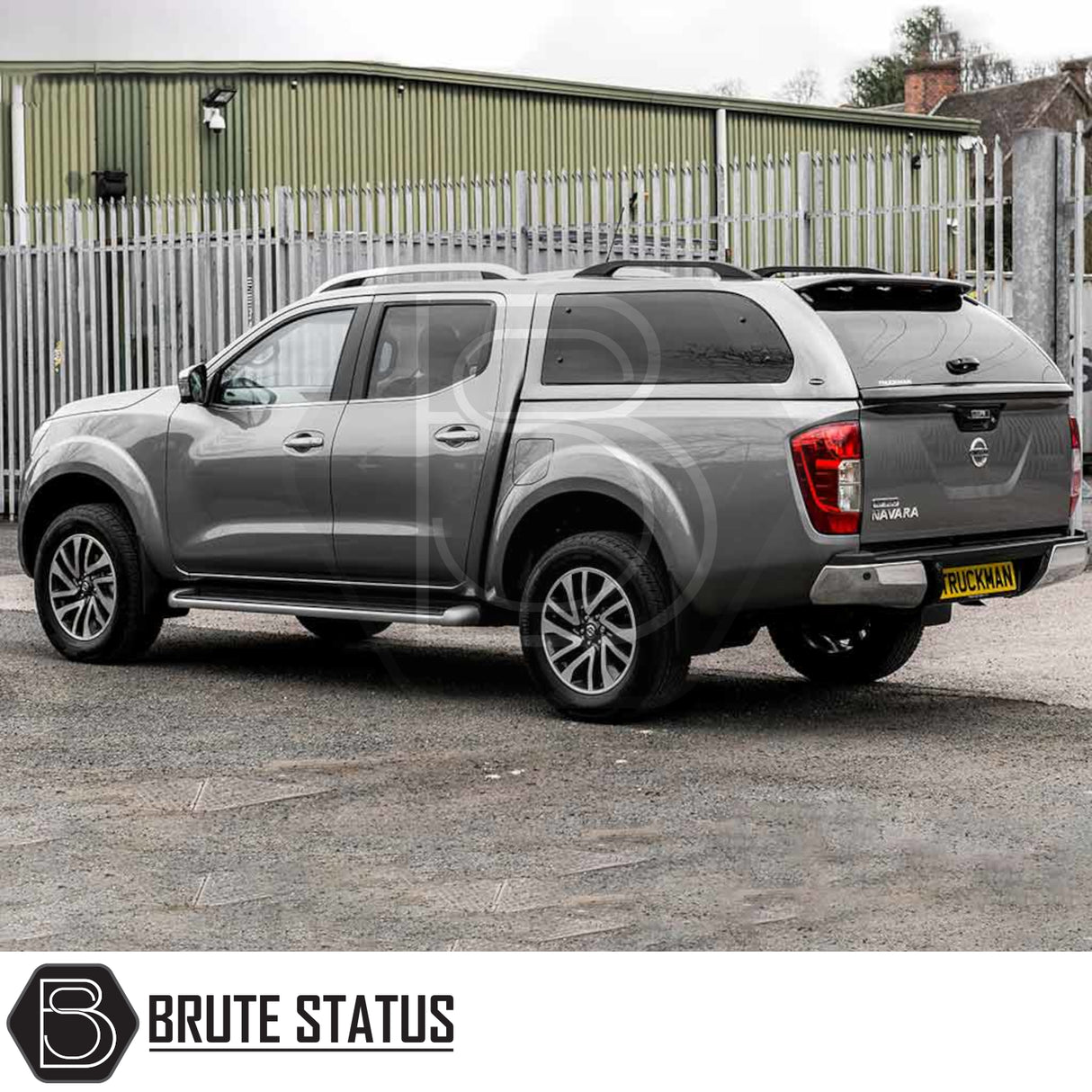 Grey Nissan Navara D40 with Truckman Grand Hardtop Canopy showcasing remote locking and tinted windows, parked on gravel in front of a security fence.