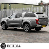Grey Nissan Navara D40 with Truckman Grand Hardtop Canopy showcasing remote locking and tinted windows, parked on gravel in front of a security fence.