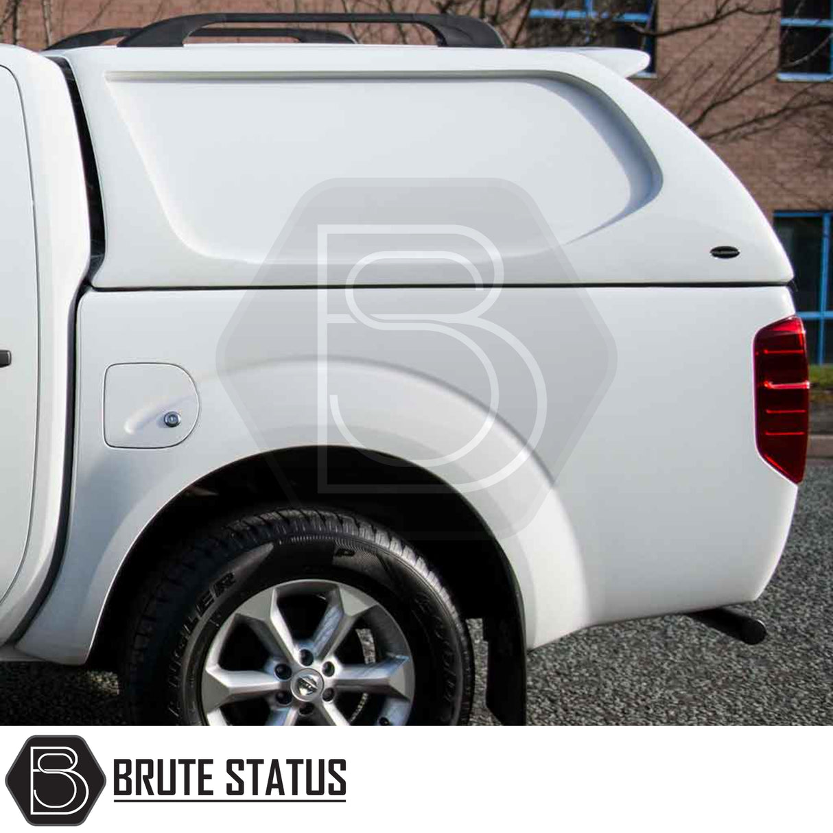 White Nissan Navara truck with Truckman L-Series hardtop canopy, showing rear wheel, tail light, and roof rack; features solid sides and remote locking.