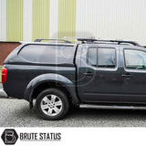Nissan Navara 2005-2015 D40 with Truckman L-Series Hardtop Canopy featuring remote locking, matching canopy, roof rack, and alloy wheels, parked in front of a building.