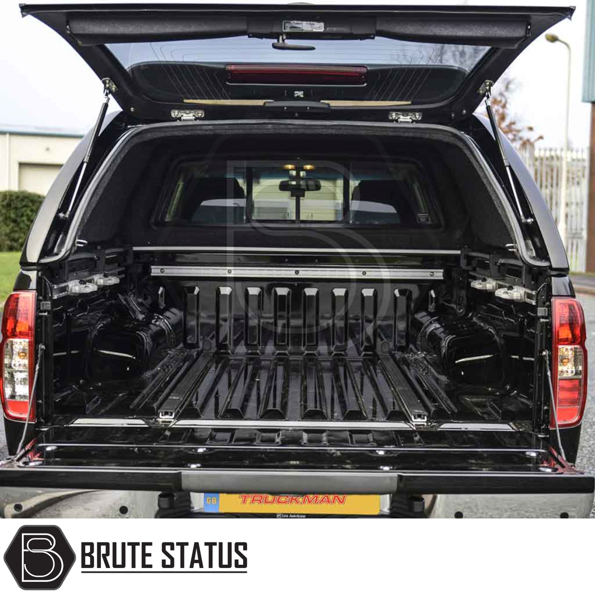 Rear view of Nissan Navara 2005-2015 D40 with open Truckman L-Series Hardtop Canopy, showcasing empty cargo bed and canopy features like remote locking and solid sides.