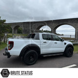 White pickup truck with Obsidian OB2 Gloss Black wheels parked by a stone viaduct, showcasing Brute Status's aftermarket customization expertise.