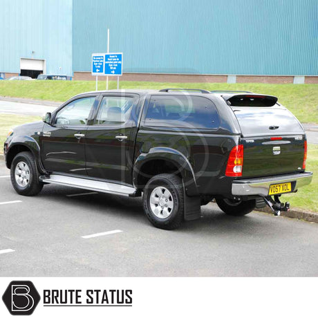 Toyota Hilux 2005-2016 MK6, MK7 Truckman Grand Hardtop Canopy with remote locking, featuring tinted pop-out windows, parked in front of an industrial building.