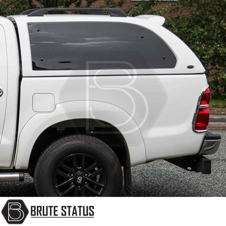 Rear view of a white Toyota Hilux with a Truckman Grand Hardtop Canopy featuring tinted windows and black alloy wheels.