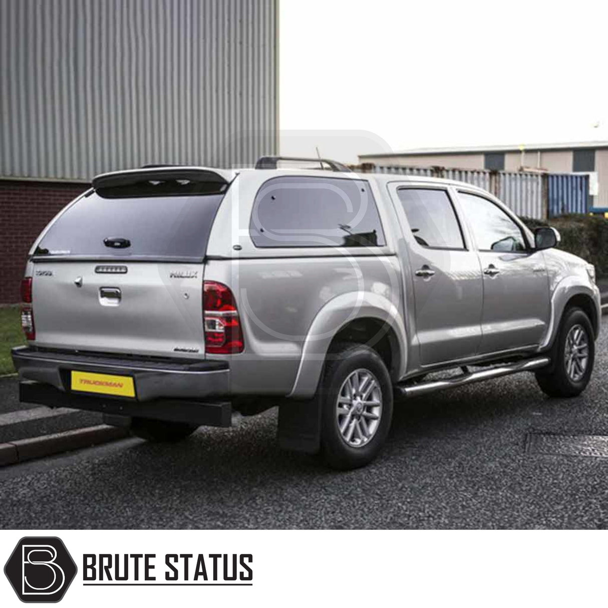 Toyota Hilux 2005-2016 MK6, MK7 Truckman Grand Hardtop Canopy with remote locking, stylish cab-high design, tinted windows, parked by industrial building.