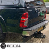 Chrome rear bumper for Toyota Hilux 2011–2014, featuring a factory-style finish, non-slip step pads with drainage channels, and direct bolt-on installation for enhanced durability and functionality