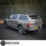 Toyota Hilux Invincible X with Truckman Grand Hardtop Canopy featuring remote locking, tinted windows, and tow hitch, parked before a metal fence.