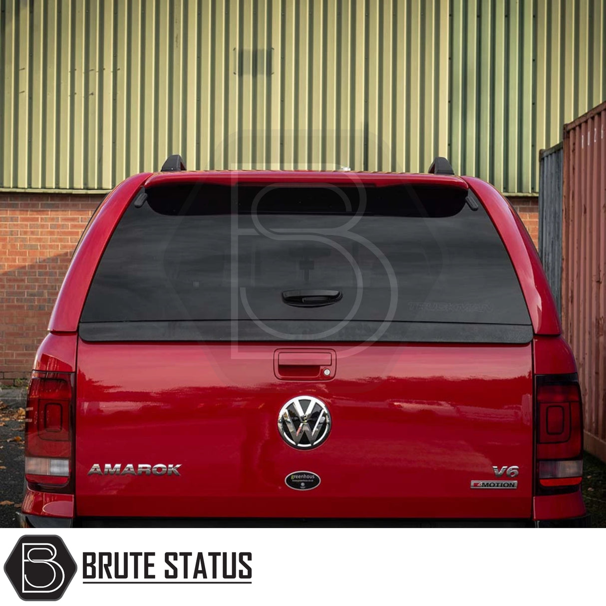 Rear view of a red Volkswagen Amarok fitted with a Truckman GLS Hardtop Canopy, featuring lockable sliding windows and a concealed lock handle, parked near a metal wall.
