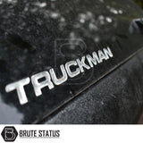 Close-up of metallic TRUCKMAN on black surface, showcasing the Volkswagen Amarok 2023+ Truckman Grand Hardtop Canopy with remote locking and Brute Status logo.